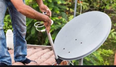 Photo of a technician carefully uninstalling a satellite dish.